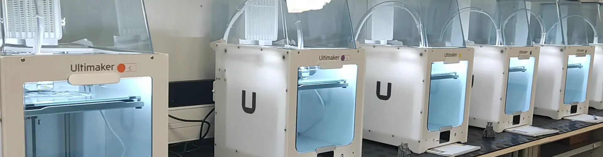 Pièce imprimée devant un parc d’imprimantes 3D